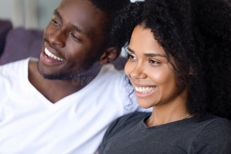 Cierre encima de los pares afroamericanos felices que se sientan junto en el sofá fotografía de archivo libre de regalías Cierre encima de los pares afroamericanos felices que se sientan junto en el sofá fotografía de archivo libre de regalías