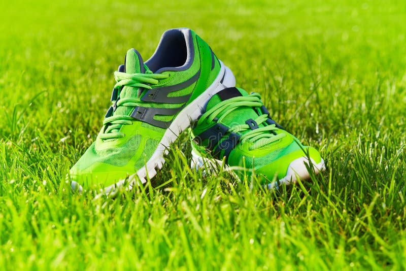 Close up new pairs of green running shoes / sneaker shoes on green grass field in the park. With space for text or design. Close up new pairs of green running shoes / sneaker shoes on green grass field in the park. With space for text or design
