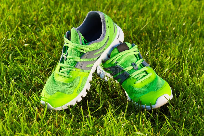 Close up new pairs of green running shoes / sneaker shoes on green grass field in the park. With space for text or design. Close up new pairs of green running shoes / sneaker shoes on green grass field in the park. With space for text or design