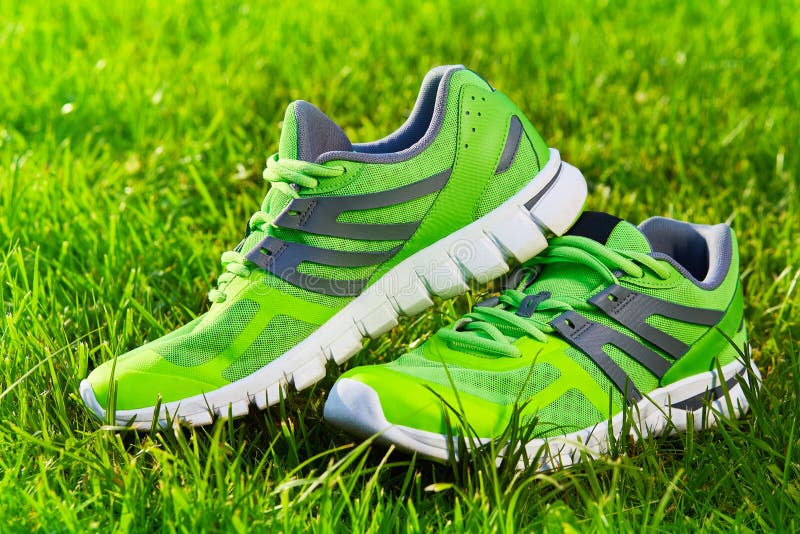 Close up new pairs of green running shoes / sneaker shoes on green grass field in the park. With space for text or design. Close up new pairs of green running shoes / sneaker shoes on green grass field in the park. With space for text or design