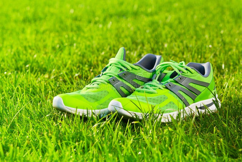 Close up new pairs of green running shoes / sneaker shoes on green grass field in the park. With space for text or design. Close up new pairs of green running shoes / sneaker shoes on green grass field in the park. With space for text or design