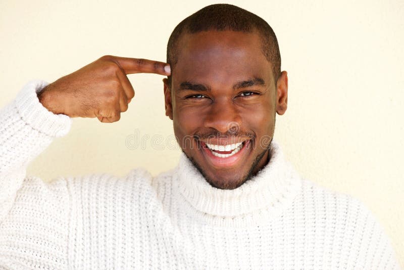 Close up portrait of handsome young black man with finger pointing to head. Close up portrait of handsome young black man with finger pointing to head