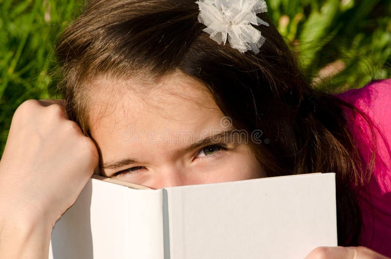 Girl covering her face with a white paper and take a break from learning. Girl covering her face with a white paper and take a break from learning