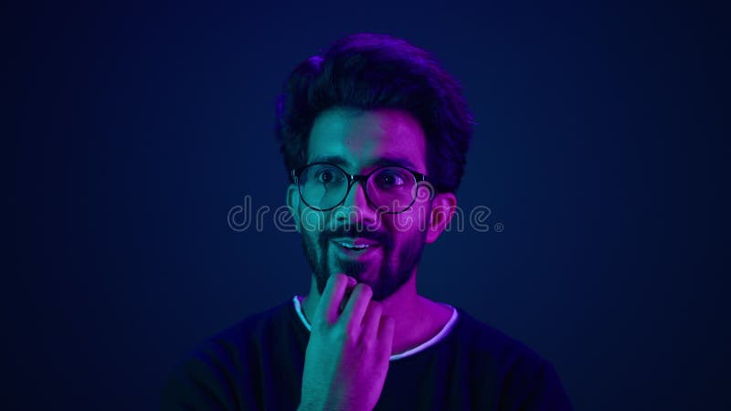 Cierre retrato masculino en neon studio fondo ultravioleta fondo azul musulmán arabio sorprendido tipo asombrado