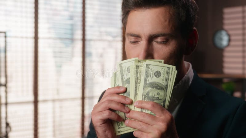 Cierre a un hombre de negocios rico y maduro contando dólares oliendo aroma de billetes en el despacho hombre de negocios metrajes