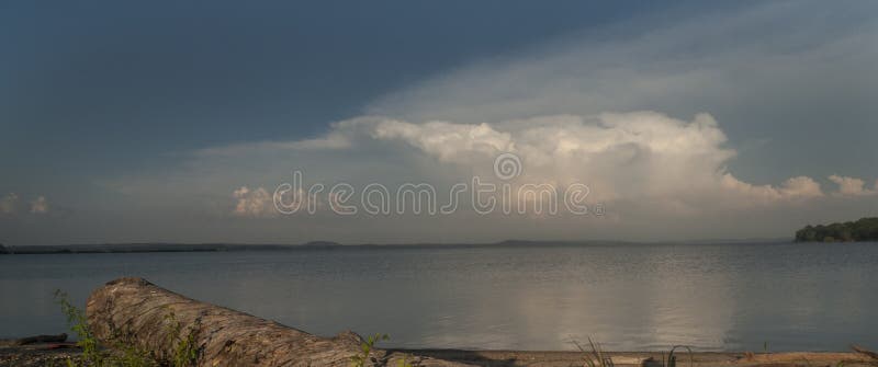 Cieux orageux au-dessus d'un lac avec le bois de flottage sur le rivage photos stock Cieux orageux au-dessus d'un lac avec le bois de flottage sur le rivage photos stock