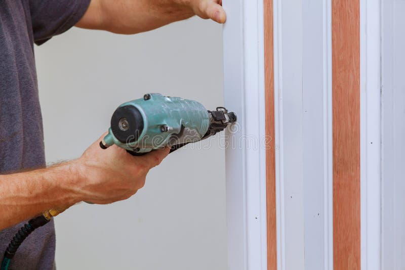 Carpenter using a brad nail gun to complete framing trim Air gun for nailing using nail gun. Carpenter using a brad nail gun to complete framing trim Air gun for nailing using nail gun