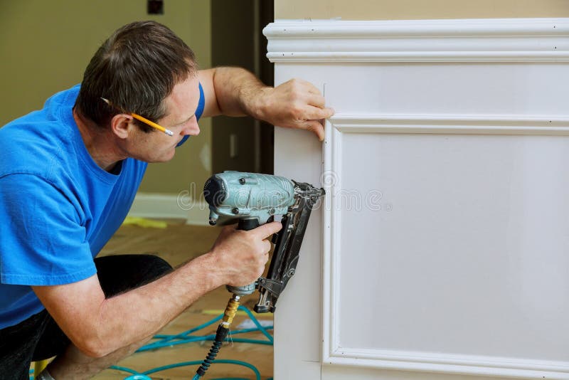 Carpenter using a brad nail gun to complete framing trim Air gun for nailing. Carpenter using a brad nail gun to complete framing trim Air gun for nailing