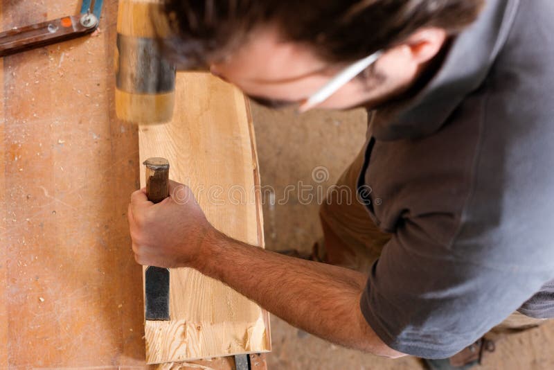 Carpenter working with a chisel and hammer in his workshop. Carpenter working with a chisel and hammer in his workshop