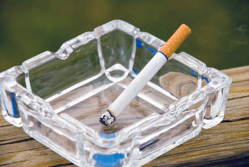 A cigarette burning in a glass ashtray.