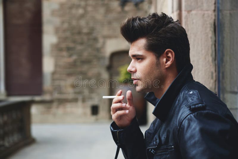 Cigarrillo que se sostiene modelo masculino hermoso en la mano que parece pensativa y seria imagen de archivo libre de regalías Cigarrillo que se sostiene modelo masculino hermoso en la mano que parece pensativa y seria imagen de archivo libre de regalías
