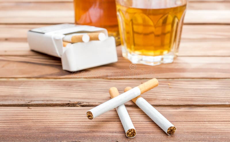 Cigarettes with alcohol drinks on wooden table. Social issues. Cigarettes with alcohol drinks on wooden table. Social issues.