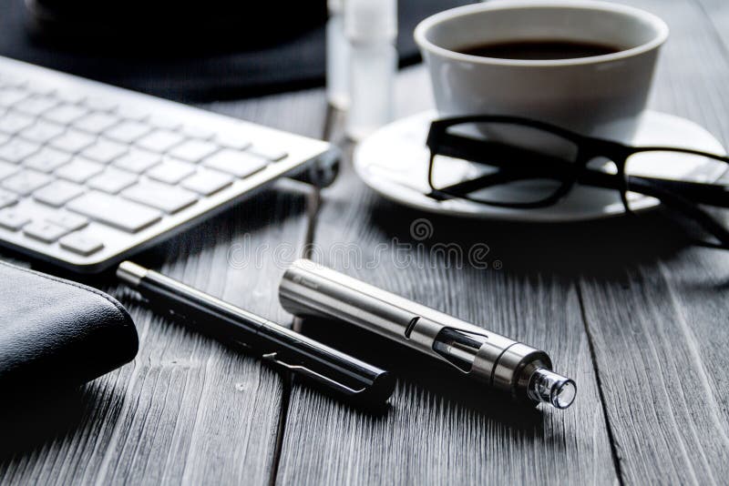 Electronic cigarettes and mens dark wooden desktop close up. Electronic cigarettes and mens dark wooden desktop close up