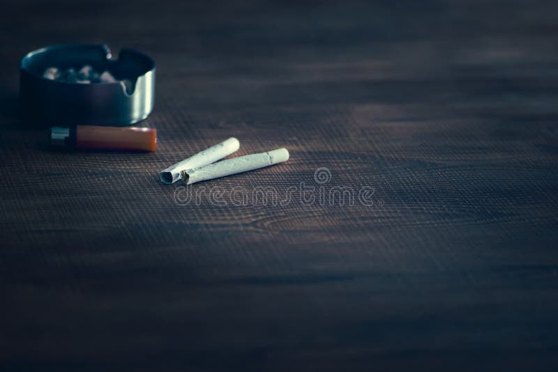 Handmade cigarettes on table with lighter and ashtray. Natural tobacco cigarettes. Handmade cigarettes on table with lighter and ashtray. Natural tobacco cigarettes