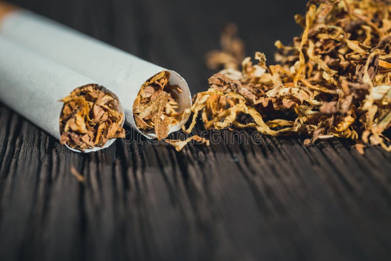 Homemade cigarettes and tobacco on the brown wooden table, close up with copy space. Homemade cigarettes and tobacco on the brown wooden table, close up with copy space