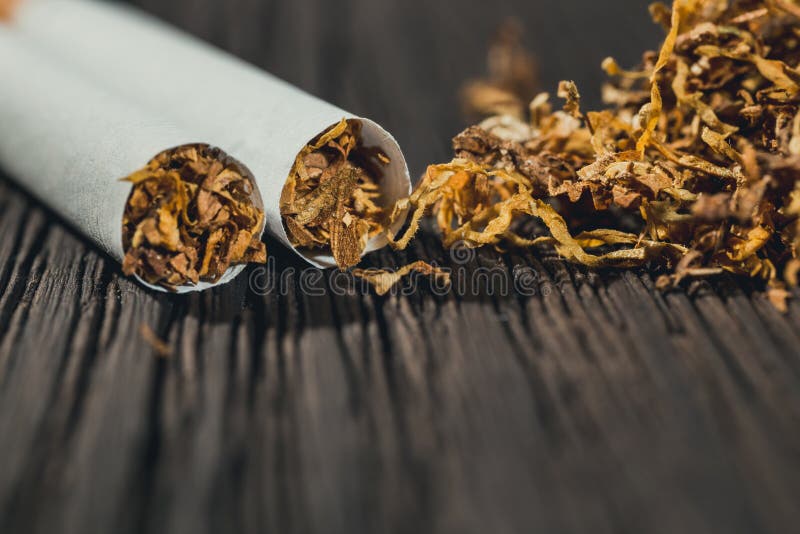Homemade cigarettes and tobacco on the brown wooden table, close up with copy space. Homemade cigarettes and tobacco on the brown wooden table, close up with copy space