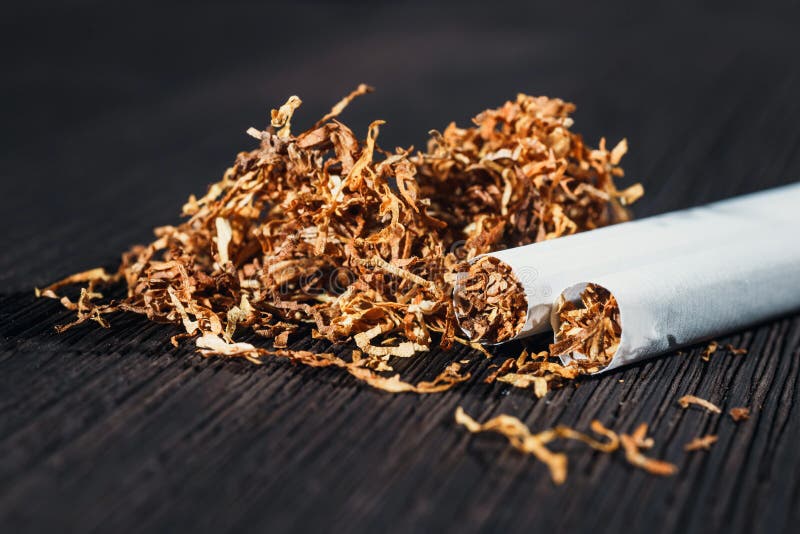 Homemade cigarettes and tobacco on the brown wooden table, close up with copy space. Homemade cigarettes and tobacco on the brown wooden table, close up with copy space