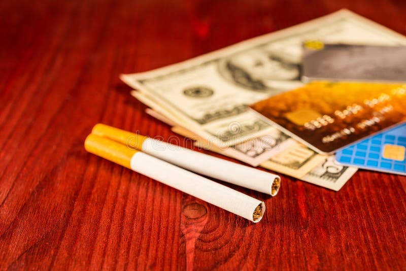 Cigarettes and payment cards on a several dollar on the table. Close up view. Cigarettes and payment cards on a several dollar on the table. Close up view
