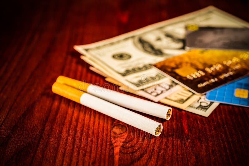 Cigarettes and payment cards on a several dollar on the table. Close up view. Cigarettes and payment cards on a several dollar on the table. Close up view