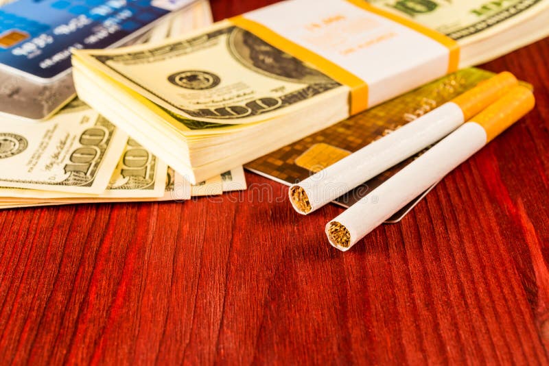 Cigarettes and payment cards on a several dollar on the table. Close up view. Cigarettes and payment cards on a several dollar on the table. Close up view