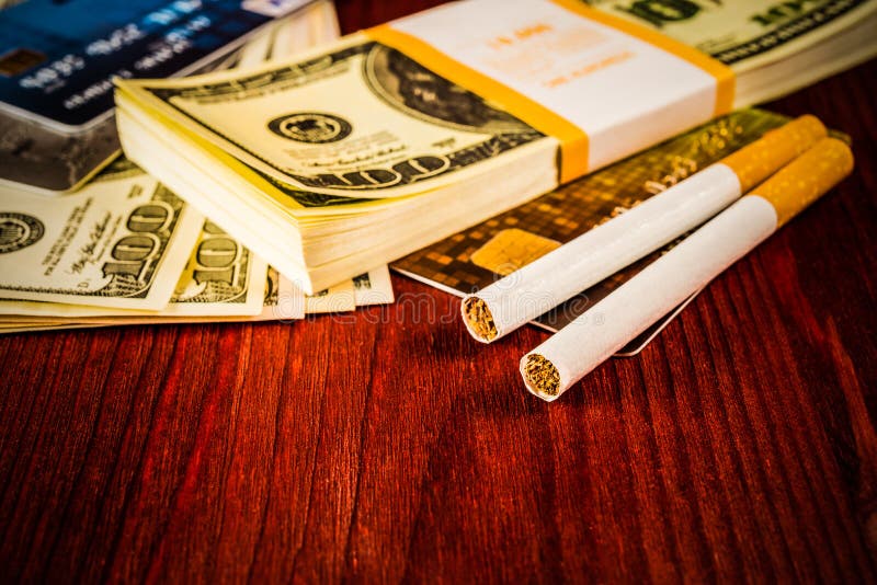 Cigarettes and payment cards on a several dollar on the table. Close up view. Cigarettes and payment cards on a several dollar on the table. Close up view