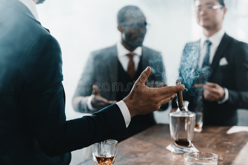 Cigarro que fuma del hombre de negocios con el equipo multicultural del negocio imagen de archivo Cigarro que fuma del hombre de negocios con el equipo multicultural del negocio imagen de archivo