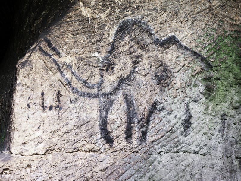 Abstract children art in sandstone cave. Black carbon mammoth paint of human hunting on sandstone wall, copy of prehistoric picture. Abstract children art in sandstone cave. Black carbon mammoth paint of human hunting on sandstone wall, copy of prehistoric picture.