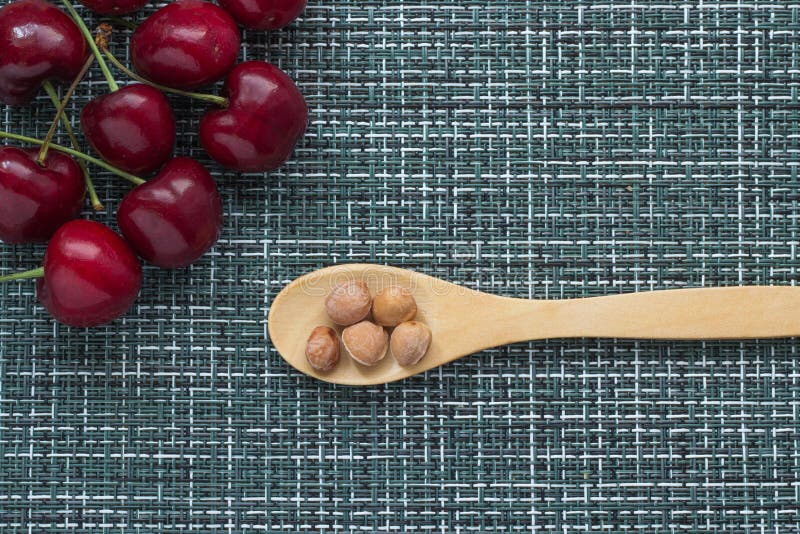 Ciliege mature su un fondo di vimini e su un cucchiaio di legno a destra con i noccioli delle bacche, primo piano fotografie stock libere da diritti Ciliege mature su un fondo di vimini e su un cucchiaio di legno a destra con i noccioli delle bacche, primo piano fotografie stock libere da diritti
