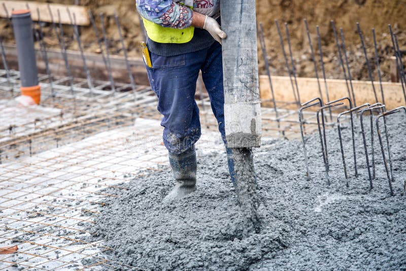 Cimento ou concreto de derramamento do trabalhador de construção civil com tubo de bomba Cimento ou concreto de derramamento do trabalhador de construção civil com tubo de bomba