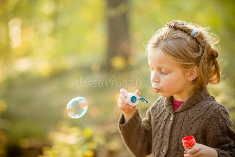 Cinco burbujas de jabón de la muchacha caucásica del niño de los años que soplan al aire libre en la puesta del sol - niñez despr fotos de archivo Cinco burbujas de jabón de la muchacha caucásica del niño de los años que soplan al aire libre en la puesta del sol - niñez despr fotos de archivo