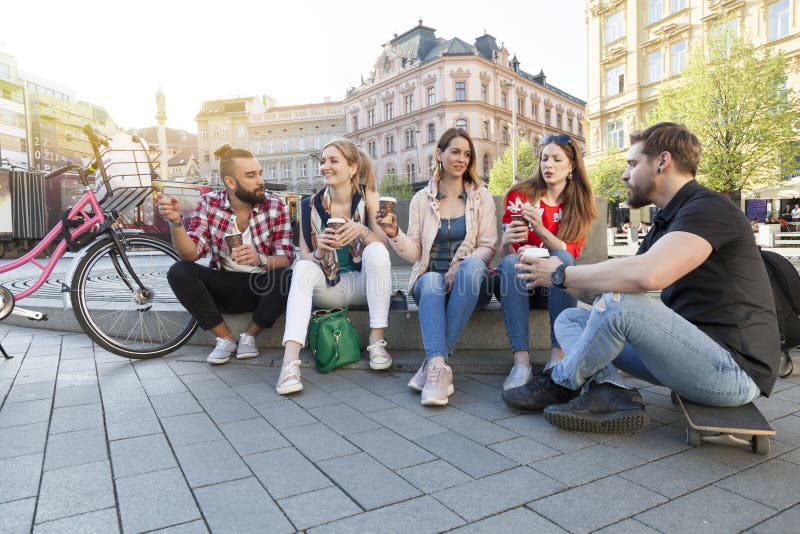 Cinco mejores amigos tienen una reunión en la calle de la ciudad que beben para llevarse el café para ir fotos de archivo libres de regalías Cinco mejores amigos tienen una reunión en la calle de la ciudad que beben para llevarse el café para ir fotos de archivo libres de regalías