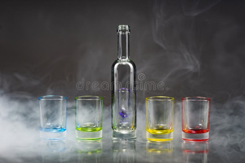 Cinco vidros de tiro vazios coloridos e a garrafa pequena colocaram o sym imagem de stock Cinco vidros de tiro vazios coloridos e a garrafa pequena colocaram o sym imagem de stock