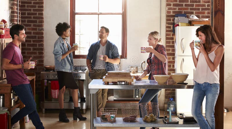 Cinq amis se tiennent traînants dans la cuisine, longueur quarte photo libre de droits Cinq amis se tiennent traînants dans la cuisine, longueur quarte photo libre de droits