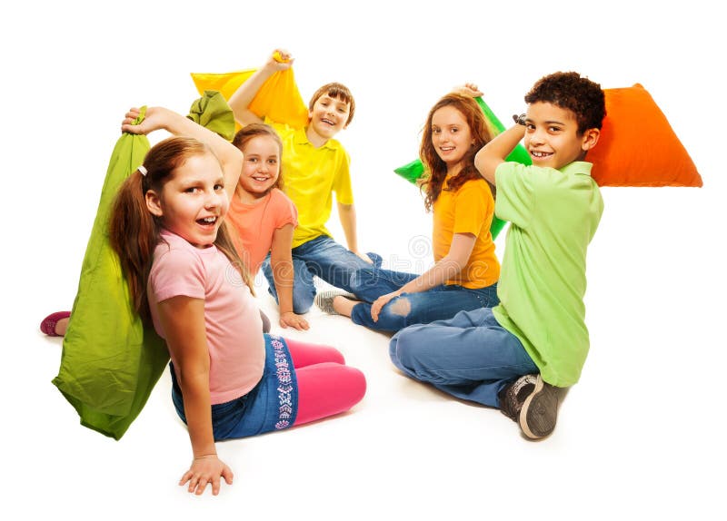 Happy five teen kids, Caucasian, black and Asian, boys and girls fighting with pillows, laughing and having fun, isolated on white. Happy five teen kids, Caucasian, black and Asian, boys and girls fighting with pillows, laughing and having fun, isolated on white