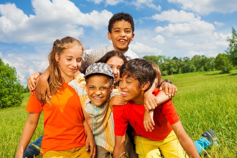Cinque bambini felici che stringono a sé insieme fuori immagine stock Cinque bambini felici che stringono a sé insieme fuori immagine stock