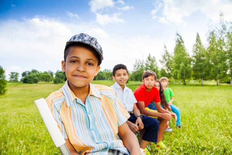 Cinque bambini felici si siedono sulle sedie nella fila all'aperto immagini stock libere da diritti Cinque bambini felici si siedono sulle sedie nella fila all'aperto immagini stock libere da diritti