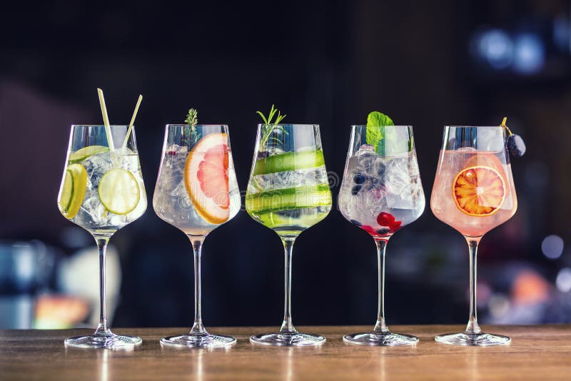 Cinque cocktail tonici del gin variopinto in vetri di vino sul contatore della barra fotografia stock