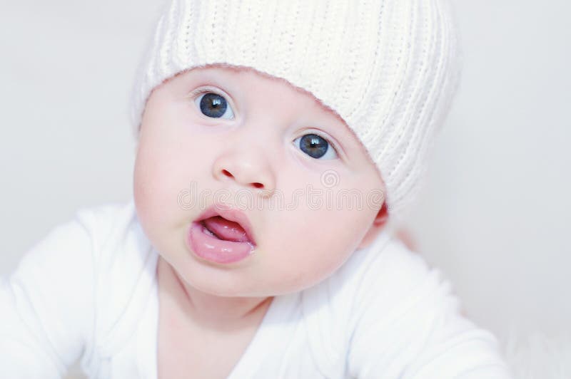 Cinque-mesi piacevoli di bambino in cappello bianco immagini stock libere da diritti Cinque-mesi piacevoli di bambino in cappello bianco immagini stock libere da diritti