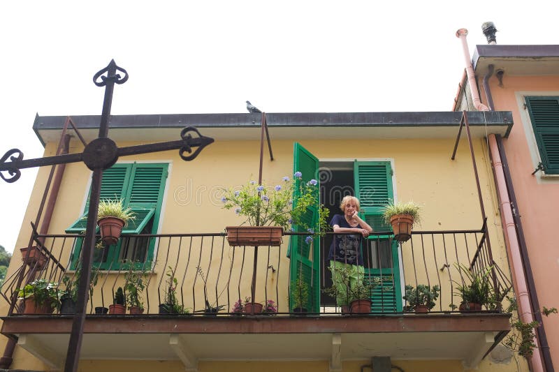 Cinque terre, vecchia italiana, appoggiata su una ringhiera di un balcone colorato con piante in vaso. immagini stock libere da diritti