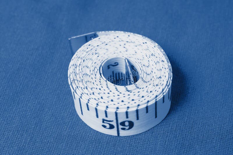 Cinta de centímetro sobre un fondo de tela gris pintado en el clásico color azul trendy del año 2020 imágenes de archivo libres de regalías Cinta de centímetro sobre un fondo de tela gris pintado en el clásico color azul trendy del año 2020 imágenes de archivo libres de regalías