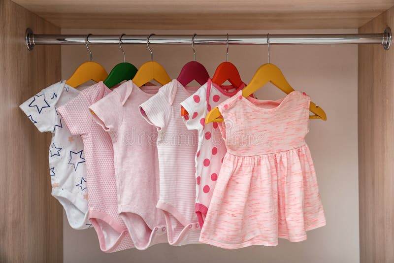 Cintres Avec Des Costumes Pour Bébé Et Des Piles De Vêtements Près Du Mur  Blanc. Espace Pour Le Texte Photo stock - Image du innocence, babyhood:  274249296