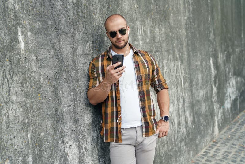 Cintura acima do retrato do indivíduo farpado corajoso bonito novo que está fora contra a parede moderna cinzenta do sótão com o fotos de stock Cintura acima do retrato do indivíduo farpado corajoso bonito novo que está fora contra a parede moderna cinzenta do sótão com o fotos de stock