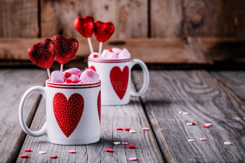 Cioccolata calda con la caramella gommosa e molle rosa in tazze con i cuori per il giorno di S. Valentino fotografia stock Cioccolata calda con la caramella gommosa e molle rosa in tazze con i cuori per il giorno di S. Valentino fotografia stock