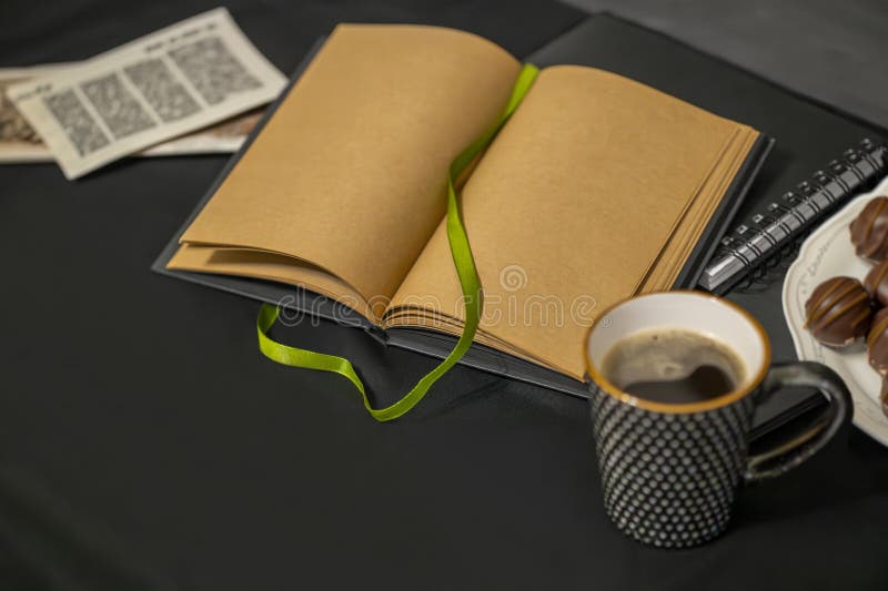 Cioccolatini da appunti una tazza di caffè e vecchi volantini su fondo nero.
