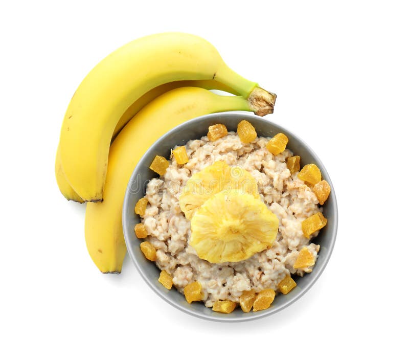 Ciotola con la farina d'avena pronta, l'ananas secco e le banane su fondo bianco fotografia stock Ciotola con la farina d'avena pronta, l'ananas secco e le banane su fondo bianco fotografia stock