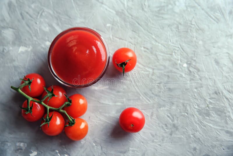Ciotola con salsa ed i pomodori ciliegia rossi su fondo grigio, vista superiore immagine stock libera da diritti Ciotola con salsa ed i pomodori ciliegia rossi su fondo grigio, vista superiore immagine stock libera da diritti