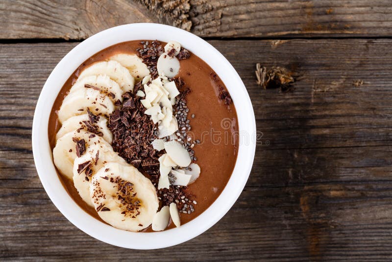 Ciotola del frullato del cioccolato con la banana, i semi di chia ed i chip della mandorla fotografia stock libera da diritti Ciotola del frullato del cioccolato con la banana, i semi di chia ed i chip della mandorla fotografia stock libera da diritti