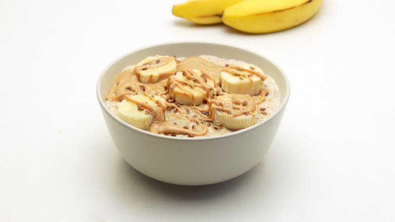 Ciotola del porridge della farina d'avena con il burro di dado e della banana immagine stock libera da diritti Ciotola del porridge della farina d'avena con il burro di dado e della banana immagine stock libera da diritti