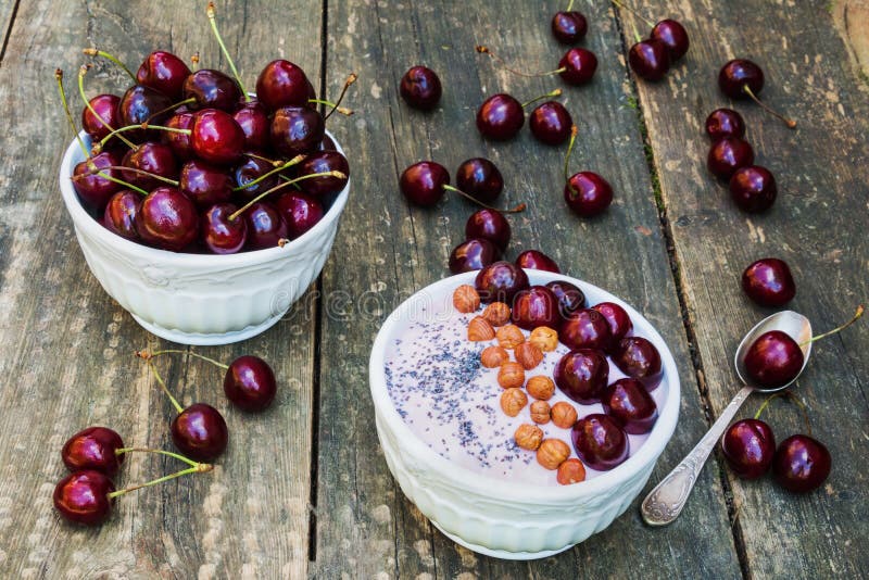Ciotola della prima colazione con yogurt, granola o muesli o fiocchi di avena, ciliege fresche e dadi Vecchia priorità bassa dell fotografia stock libera da diritti Ciotola della prima colazione con yogurt, granola o muesli o fiocchi di avena, ciliege fresche e dadi Vecchia priorità bassa dell fotografia stock libera da diritti