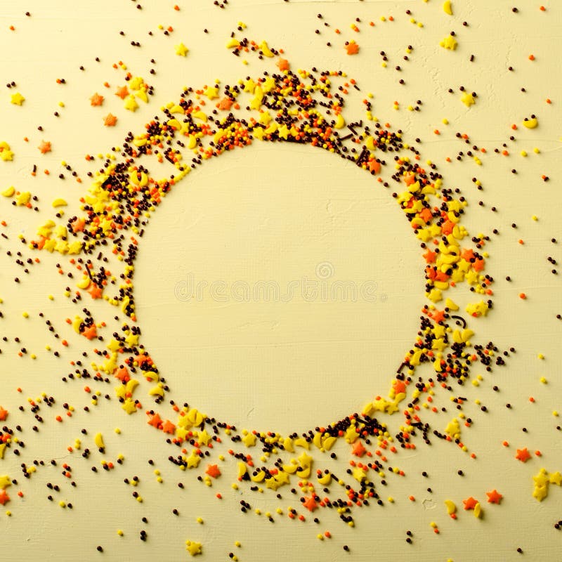 Circle frame made of sugar candies, pastry decoration on yellow background.